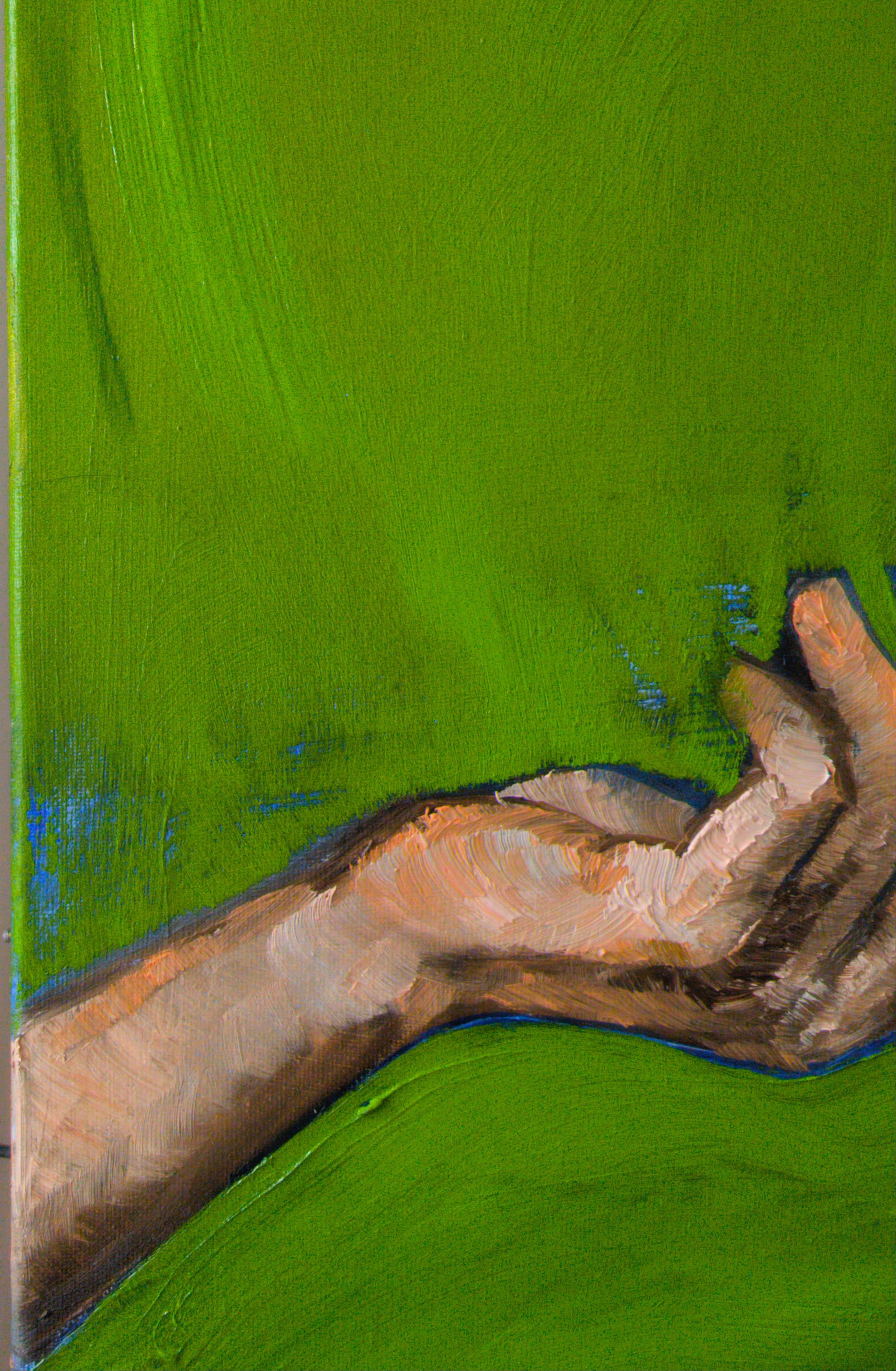 Close-up of a hand holding a brush with green paint on a surface